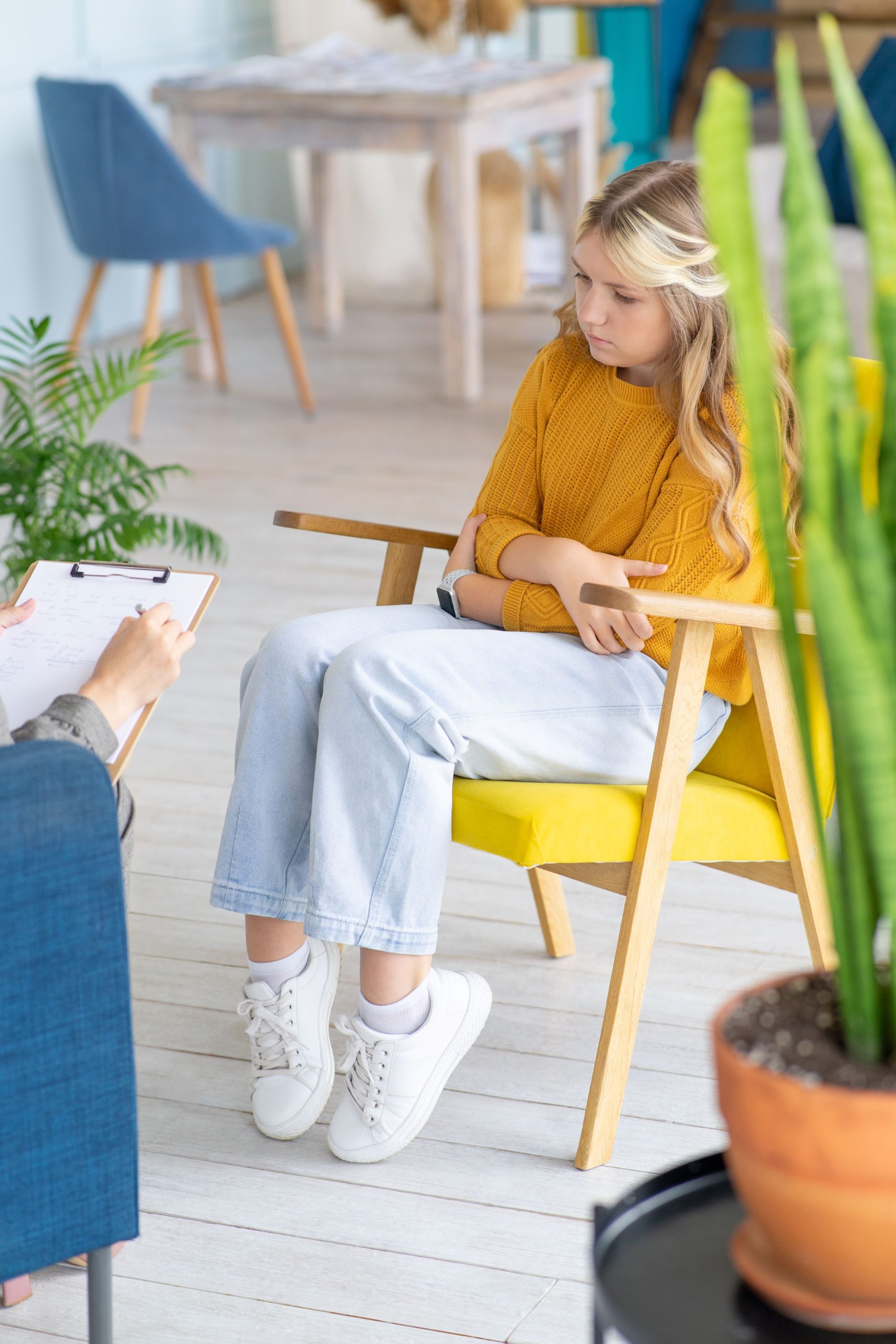 Blonde teenage girl sat in a chair with arms crossed